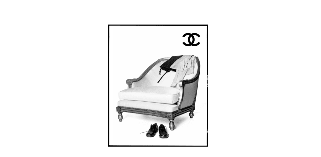 Svart-hvitt bilde av en elegant stol med klær slengt over og et par sko på gulvet, med Chanel-logo. Matthieu Blazy for Chanel: Se visningen her