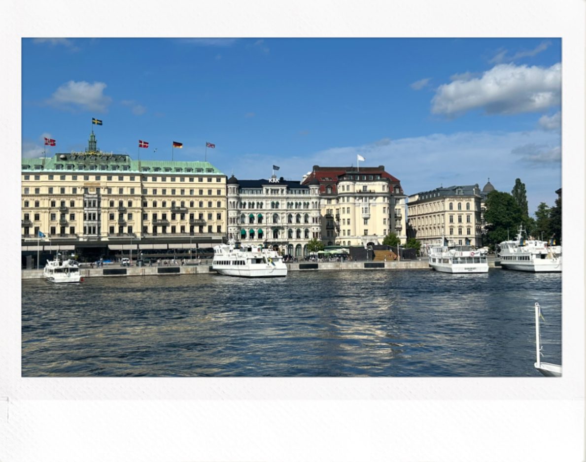 Historiske bygninger ved vannkanten i Stockholm med båter og blå himmel.