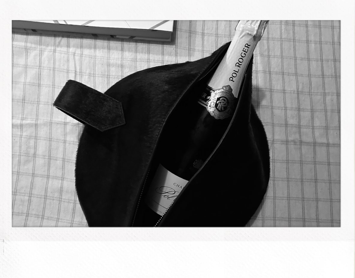 Champagneflaske fra Pol Roger i en veske på rutete underlag.